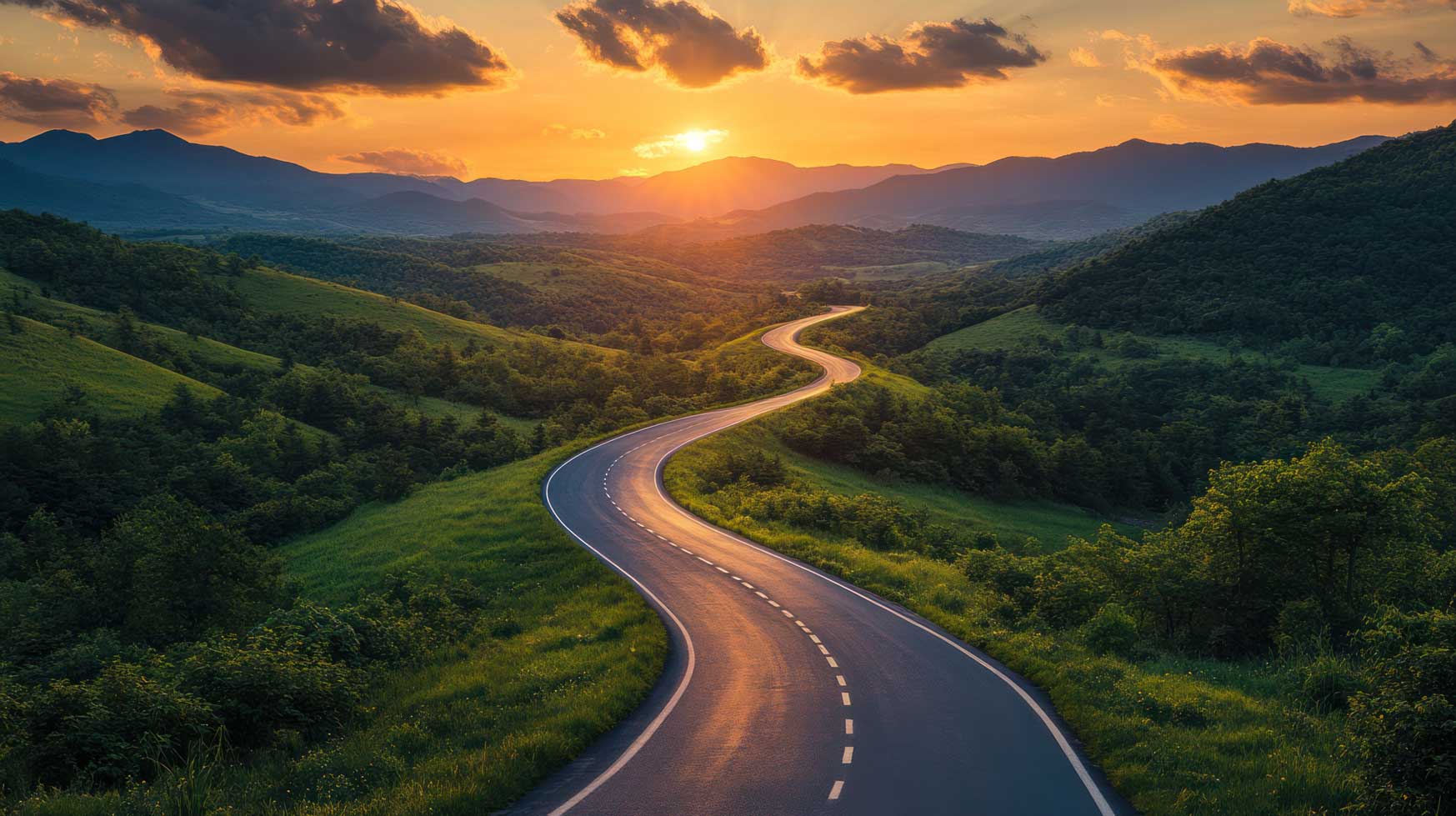 winding road through green fields with a sunset